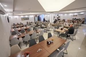 ein Raum mit Tischen und Stühlen und Menschen, die daran sitzen in der Unterkunft Erbil View Hotel in Erbil