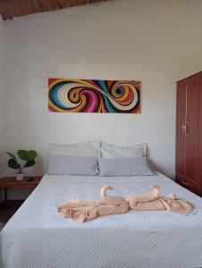 una cama con una toalla con una pintura en El Parralito hospedaje en Ciudad Lujan de Cuyo