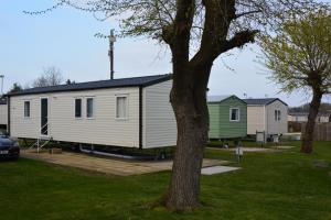 a large white house in a yard with a tree at Holiday Home at Cherry Tree Holiday Park 738 in Great Yarmouth