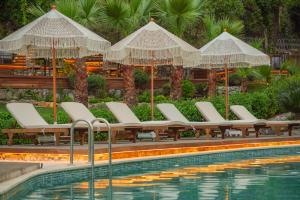 ein Schwimmbad mit weißen Liegestühlen und Sonnenschirmen in der Unterkunft Nuup Hotel in Marmaris