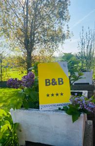 a sign for a be bc sign in a garden at Villa La Dune - Ontbijt & parking inclusief in Middelkerke