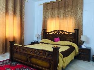 a bedroom with a wooden bed with yellow sheets and pink pillows at Pasha's house in Balad al Manşūrah