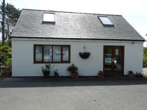 a white house with two windows and a door at Gwyndaf Holiday Cottage in Llangoed