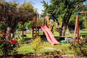 einen Spielplatz mit einer roten Rutsche in einem Park in der Unterkunft Rózsa Porta in Zengővárkony