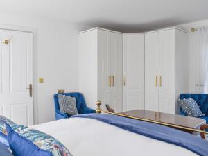 Llabedr-Dyffryn-Clwyd的住宿－Wisteria Lodge At The Shipon，一间卧室配有蓝色的椅子、一张床和一张桌子