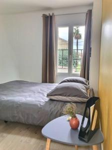 a bedroom with a bed and a table and a window at Bleu Lavande 1 - Appartement cosy ambiance village in Istres