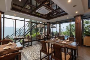 un restaurante con mesas, sillas y ventanas grandes en EBINO PULUONG RESORT en Pu Luong