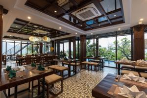 un restaurante con mesas, sillas y ventanas grandes en EBINO PULUONG RESORT, en Pu Luong