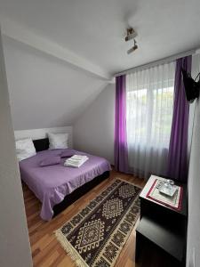sypialnia z fioletowym łóżkiem i fioletowymi zasłonami w obiekcie Casa Mihai și Clara w mieście Călimăneşti