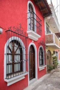 Edificio rojo con ventanas y balcón en Casa la Ermita, en Antigua Guatemala