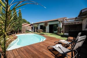 una piscina su una terrazza in legno con 2 sedie di Villa Eden Bleu - Piscine et jacuzzi privé - Logement classé 4 étoiles a Biscarrosse