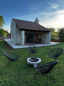 ein Haus mit zwei Stühlen und einer Feuerstelle im Gras in der Unterkunft Villa Ondina in Brtonigla