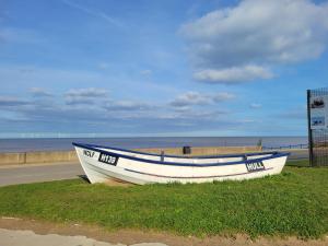 un bateau assis sur l'herbe à côté d'une plage dans l'établissement Charming 2 Bedroom Holiday Chalet, à Withernsea 10 autres photos