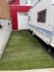 uma caravana estacionada ao lado de uma garagem vermelha e branca em Cozy Caravan em Vestmannaeyjar