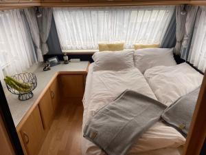 a bed in a small room with white sheets and pillows at Cozy Caravan in Vestmannaeyjar