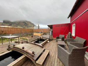 a wooden deck with chairs and a red building at Cozy Caravan in Vestmannaeyjar