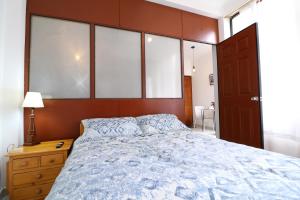a bedroom with a bed with a blue comforter and windows at Apartamento en La Candelaria - Centro Histórico in Bogotá