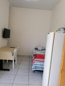 a room with a bed and a table and a refrigerator at quarto para Rapaz, centro, Sinop MT in Sinop