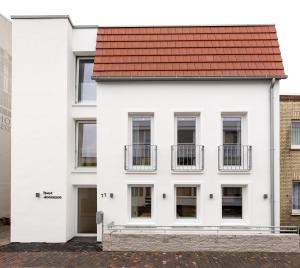 a white building with a red roof at Haus Andersen Apartment ZWEI in Norderney