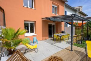 um pátio com cadeiras amarelas, uma mesa e um edifício em Chez Odette - SPA, Barbecue, Parking em Albi