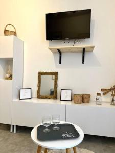 uma sala de estar com televisão e uma mesa com copos de vinho em Studio en ville em Nevers