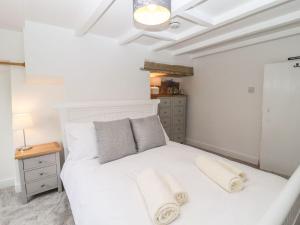 um quarto com uma cama branca e toalhas em Hideaway Cottage em Barnoldswick