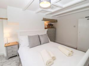 a bedroom with a white bed with towels on it at Hideaway Cottage in Barnoldswick