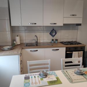 uma cozinha com armários brancos e uma mesa e cadeiras em Da Carla Dolomiti Val di Zoldo em Val di Zoldo