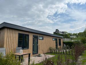 Un pequeño edificio con una mesa en un jardín. en Linked Chalet, en Oostvoorne 4 fotos más