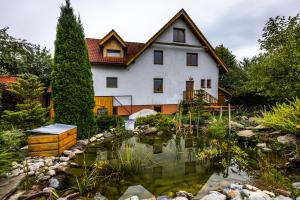 a house with a pond in front of it at Penzion Jas in Zuberec