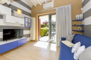 uma sala de estar com um sofá azul e uma televisão em Acquarius Resort Sirmione - MGH em Sirmione