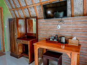 a room with a wooden table and a tv on the wall at Mertha Sari Resto & Bungalow in Klungkung
