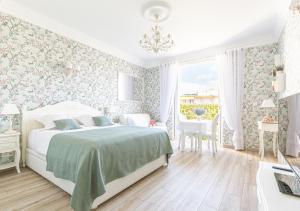 a white bedroom with a bed and a table at Croisette Palais Miramar Cannes Imperial in Cannes