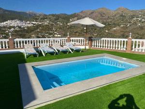 a swimming pool in a yard with chairs and an umbrella at Entre montañas in Árchez