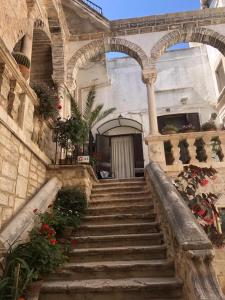 - un bâtiment en pierre avec des escaliers menant à un bâtiment fleuri dans l'établissement Corte De Ritis, à Giovinazzo