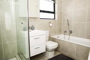 a bathroom with a toilet and a shower and a sink at Eirini Elegant - Athena Apartment Fourways in Sandton