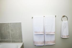 un bagno con due asciugamani bianchi appesi a un muro di Eirini Elegant - Athena Apartment Fourways a Sandton