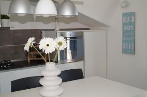 biała waza z kwiatami na stole w kuchni w obiekcie Terrazza Azzurra w mieście Vasto