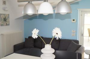 una sala de estar con sofá y un jarrón con flores. en Terrazza Azzurra, en Vasto