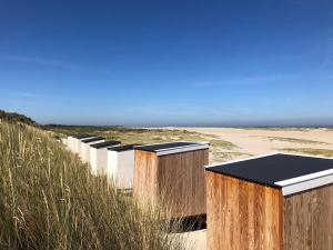 a row of wooden buildings on the beach at De Strandhoed Renesse, new & luxe chalet with garden en close to centrum & beach! in Renesse
