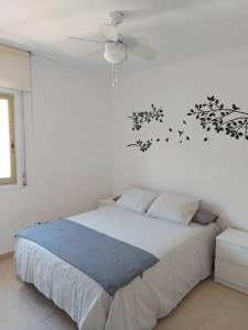 a white bedroom with a bed and a ceiling fan at Apartamentos CT in Salou
