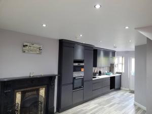 a black and white kitchen with a fireplace at Cottage by the sea Greencastle in Greencastle