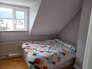 a bedroom with a bed with a colorful comforter at Cottage by the sea Greencastle in Greencastle