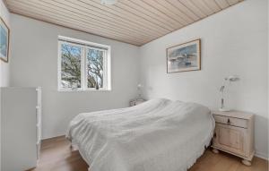 a white bedroom with a bed and a window at Holiday Home Stenbjerg Kirkevej in Stenbjerg