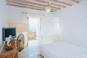 a white bedroom with a bed and a television at Dreamy Boho 5bed Villa with Pool and Ocean View in Mýkonos City