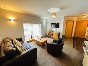a living room with a leather couch and a table at The Old Salt House, Flat1 in Wick