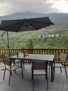 einen Tisch und Stühle auf einem Balkon mit Sonnenschirm in der Unterkunft V&V RentRoom Design in Gignod