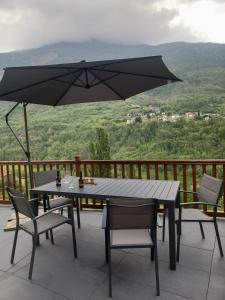 una mesa y sillas en un balcón con sombrilla en V&V RentRoom Design, en Gignod