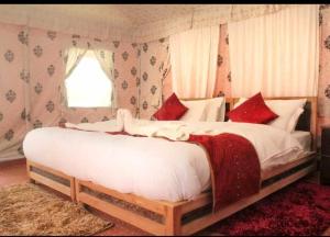 1 dormitorio con 1 cama blanca grande con almohadas rojas en Wooden Nest Cottage Hunder, Nubra Valley en Nubra