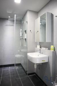 a bathroom with a white sink and a shower at Homesuite' Home at Jesselton Quay in Kota Kinabalu